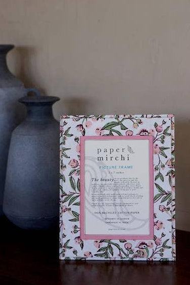 Decorative Photo Frame with floral design and text on a wooden surface with vases in the background