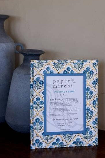 Decorative picture frame with intricate blue and white design on a wooden surface.